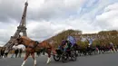 Sejumlah orang mengendarai kereta kuda melintas di depan Menara Eiffel saat mengikuti parade kuda ke-20 di Paris, Prancis (19/11). Aneka jenis kuda ikut meramaikan acara yang digelar setiap tahun ini. (AFP Photo/Thomas Samson)