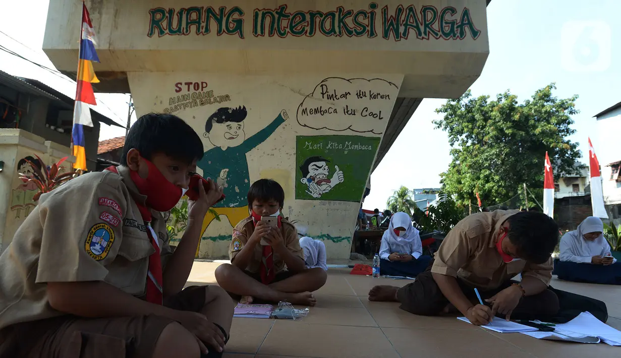 Para siswa belajar di kolong rel kereta api Mangga Besar, Jakarta,Rabu (19/8/2020). Proses belajar siswa tersebut menggunakan modem paket internet wifi gratis yang disediakan untuk mengikuti pembelajaran jarak jauh. (merdeka.com/Imam Buhori)