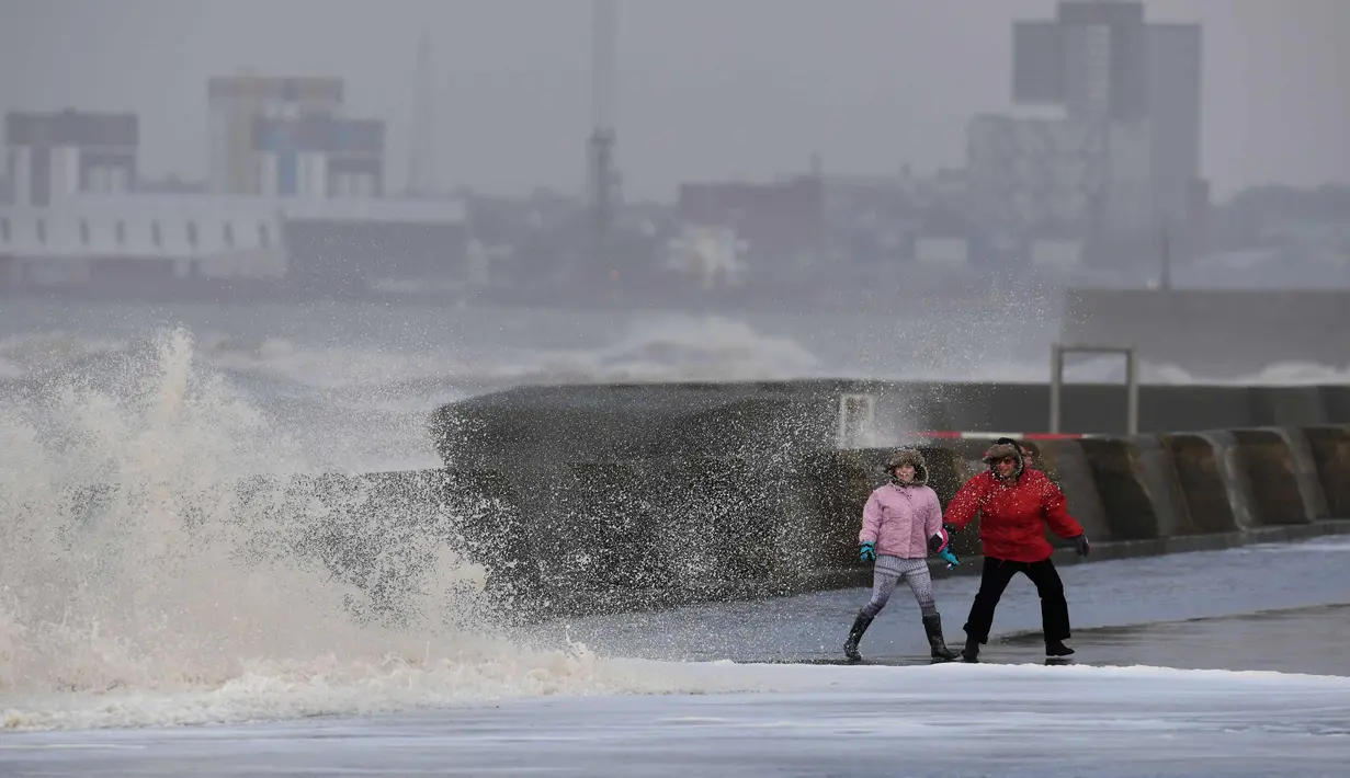 Dua warga menyaksikan ombak besar yang disebabkan badai Eleanor di sepanjang pinggir laut di New Brighton, Inggris barat laut (3/1). (AFP Photo/Paul Ellis)
