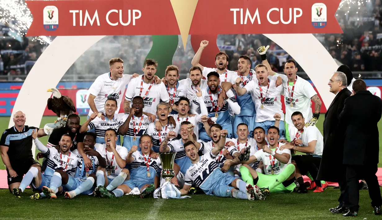 Pemain Lazio dan staf merayakan kemenangan dengan maskot mereka, burung elang dan trofi Coppa Italia pada akhir babak final yang mempertemukan Atalanta dan Lazio di Stadio Olimpico, Rabu (15/5/2019). Lazio keluar sebagai juara Coppa Italia setelah mengalahkan Atalanta 2-0. (Isabella BONOTTO/AFP)