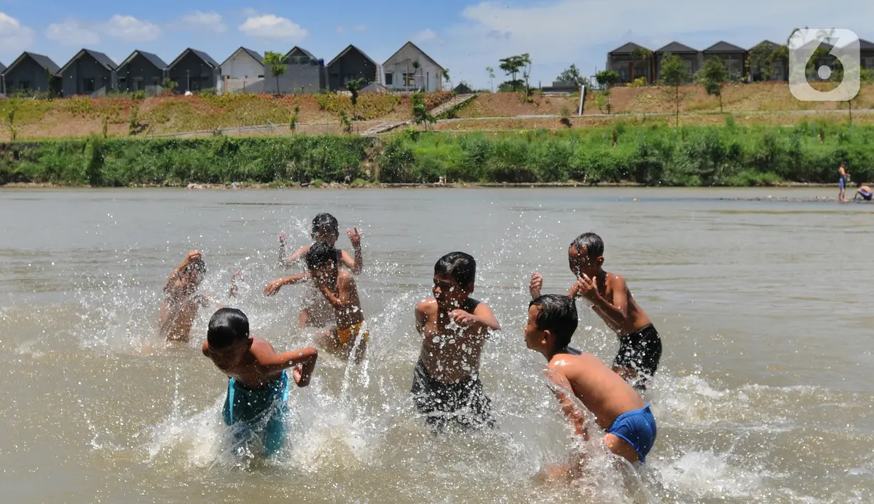 Anak-anak bermain pada aliran Sungai Cisadane di kawasan Keranggan, Setu, Tangerang Selatan, Banten, Minggu (20/3/2022). Cuaca panas terik dimanfaatkan mereka untuk berendam sambil bermain. (merdeka.com/Arie Basuki)