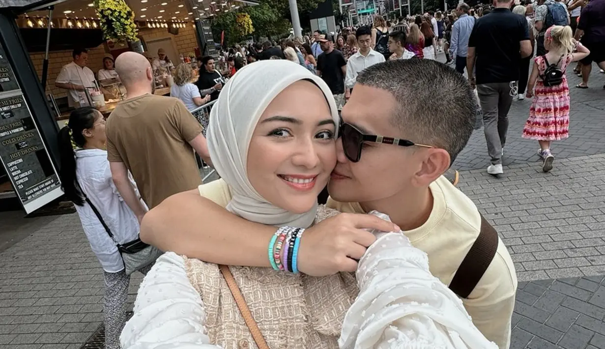 Tidak hanya berdua, Citra Kirana dan Rezky Aditya ajak anaknya ke Inggris. Namun ketika nonton konser Taylor Swift, pasangan ini menikmati momen berdua. Sebelum masuk ke stadion, Citra Kirana dan Rezky Aditya nikmati jajanan. Berpose sembari peluk dan cium Citra Kirana, Rezky Aditya romantis. Lantaran awet muda, tentu banyak yang percaya jika disebut bahwa keduanya belum menikah. (Liputan6.com/IG/@citraciki)