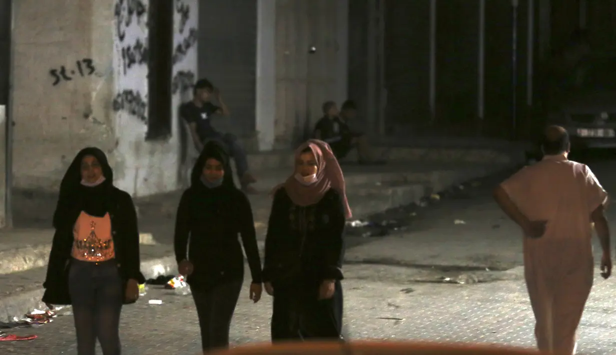 Sejumlah mengenakan masker saat berjalan ke rumah keluarga mereka selama penguncian yang diberlakukan selama pandemi virus corona, di kamp pengungsi Shati, di Kota Gaza, Selasa, (1/9/2020). (AP Photo/Adel Hana)