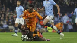 Pemain Real Madrid, Vinicius Junior jatuh saat terjegal kiper Manchester City, Ederson dalam laga leg 1 babak playoff Liga Champions 2024/2025 di Etihad Stadium, Manchester, Inggris, Rabu (12/02/2025) WIB. (AP Photo/Darren Staples)