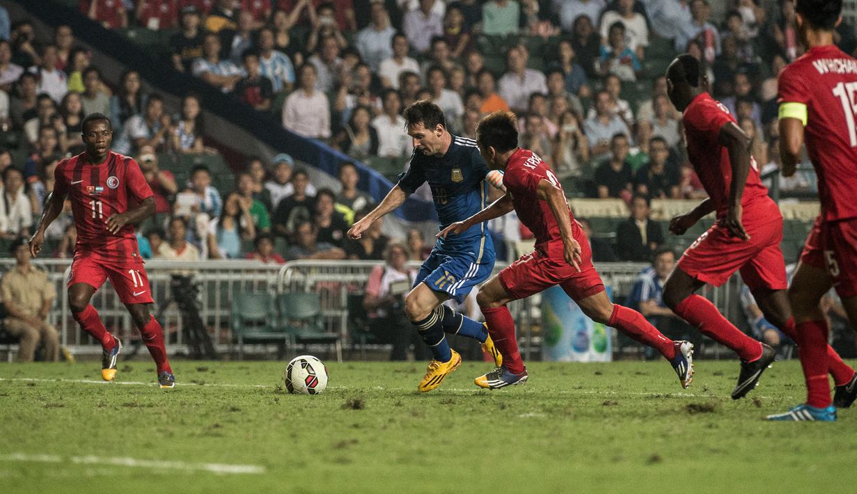 Striker Argentina, Lionel Messi (tengah) berusaha melewati pemain Timnas Hong Kong pada laga persahabatan internasional di Hong Kong Stadium, Hong Kong (14/10/2014). (AFP/Anthony Wallace)