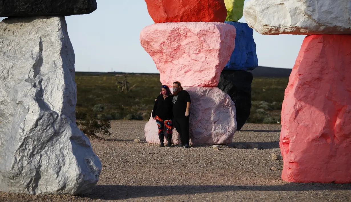Pengunjung berfoto di instalasi seni Seven Magic Mountains karya seniman Ugo Rondinone di Las Vegas, Amerika Serikat, Selasa (7/4/2020). Instalasi seni Seven Magic Mountains terlihat sangat memukau di kamera. (AP Photo/John Locher)