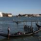 Seorang gondolier mendayung gondola di dekat gereja Santa Maria della Salute di Venesia pada 20 Mei 2021.  Turis kembali berdatangan menikmati keindahan Venesia, yang sering dijuluki kota paling romantis di dunia, setelah Italia menghapus kewajiban karantina bagi pendatang. (Marco Bertorello/AFP)