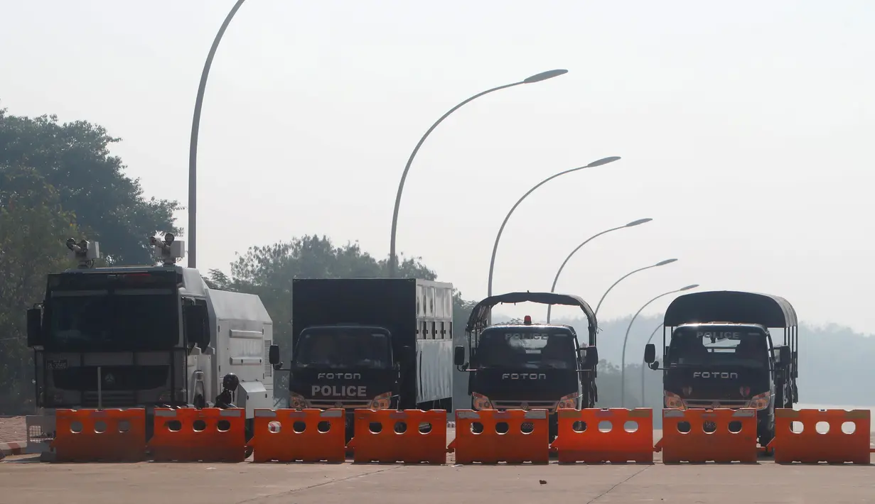 Kendaraan pengendali kerusuhan polisi dan truk pengangkut diparkir di jalan menuju gedung parlemen di Naypyitaw, Myanmar (2/2/2021). Militer Myanmar juga enahan politisi senior termasuk peraih Nobel dan pemimpin de facto Aung San Suu Kyi. (AP Photo)