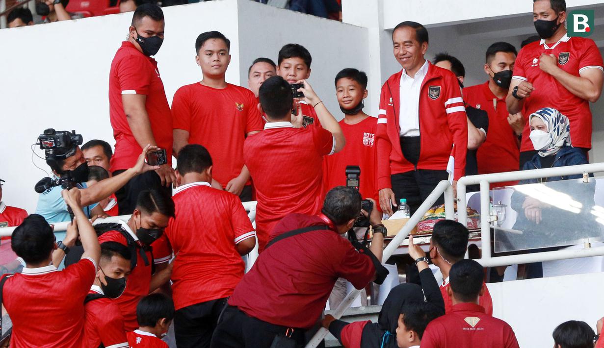 Presiden RI, Joko Widodo, memberikan senyuman saat melayani permintaan foto bersama suporter cilik di sela-sela rehat babak pertama pertandingan Timnas Indonesia melawan Thailand pada laga Piala AFF 2022 di Stadion Utama Gelora Bung Karno (SUGBK), Jakarta, Kamis (29/12/2022). (Bola.com/M Iqbal Ichsan)