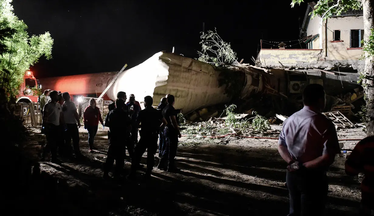 Warga melihat rumah yang dihantam kereta di Desa Adendro, Yunani, Minggu (14/5). Kecelakaan tersebut menewaskan empat orang dan melukai lima lainnya. (AP/Giannis Papanikos)