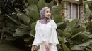 Perpaduan celana kulot dengan atasan blouse lengan lonceng warna putih bikin tampilan kondangan kian memesona. Tambahkan pula hijab pashmina warna lebih gelap dan heels. (Instagram/emyaghnia).