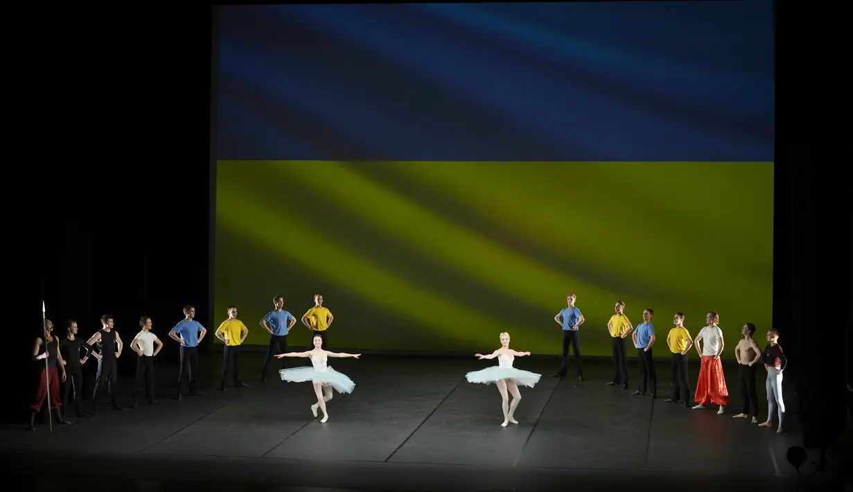Penari Ukraina dari Balet Kota Kiev tampil di depan bendera Ukraina yang diproyeksikan ke layar di Theatre de Chatelet, di Paris (8/3/2022). Pertunjukan ini sebagai bagian dari acara malam untuk mendukung Ukraina setelah invasi Rusia. (AP Photo/Thibault Camus)