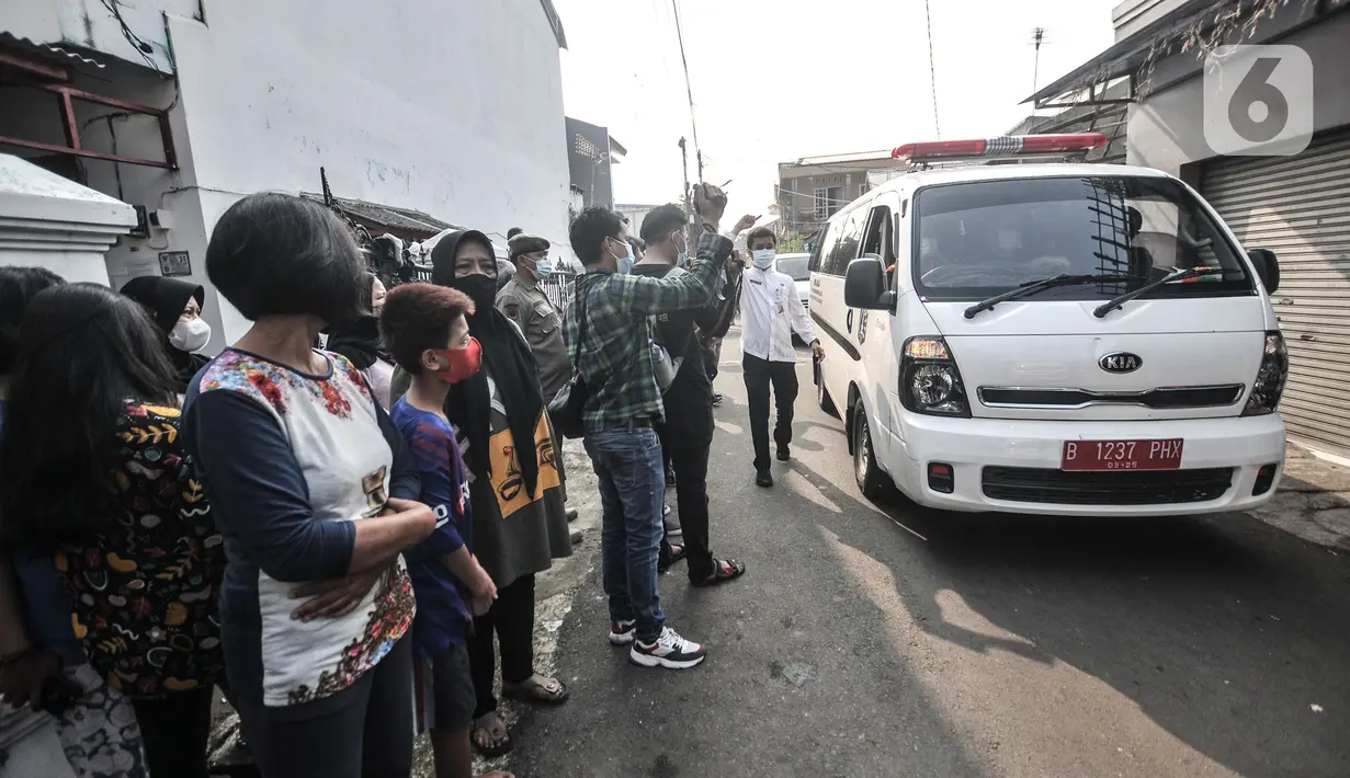 Warga menyaksikan mobil ambulans berisi jenazah Trio meninggalkan lokasi makam di Buaran, Jakarta Timur, Senin (24/5/2021). Jenazah Trio yang meninggal sehari setelah disuntik vaksin AstraZeneca akan menjalani autopsi di RSCM guna memastikan penyebab kematiannya. (merdeka.com/Iqbal S. Nugroho)