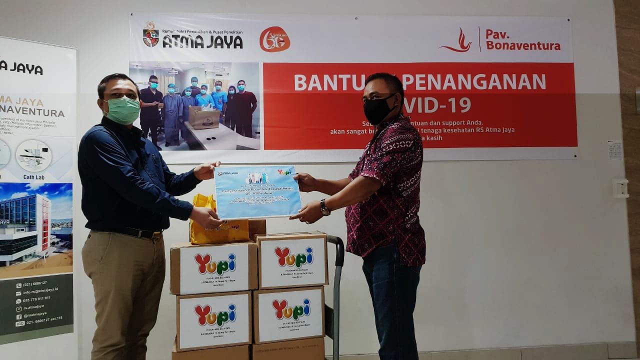 Manager Umum RS. Atma Jaya Mardiansyah (kiri) secara simbolis   menerima APD dari Yupi yang diwakili Assistant Promotion Manager Yupi Indo Jelly Gum Tri Pantja Djaya di RS Atma Jaya, Pluit,  Jakarta (15/6/20)