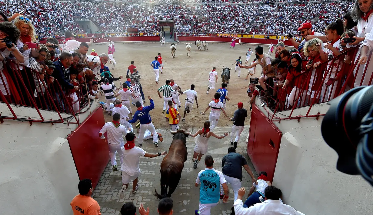 Sejumlah peserta berlari menghindari serudukan banteng selama hari ketiga Festival San Fermin di Pamplona, Spanyol utara, (9/7). Ratusan orang dari seluruh dunia  setiap tahunnya ambil bagian dalam Festival Adu Banteng, San Fermin. (AFP Photo/Jose Jordan)
