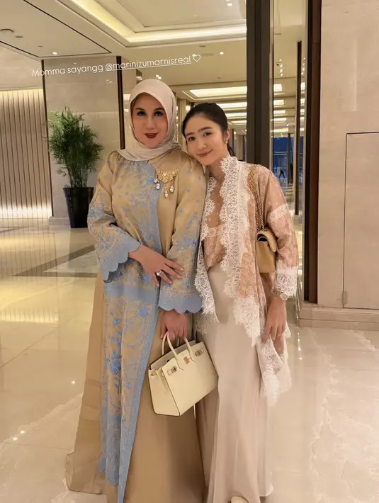 Marini Zumarnis tampil mengenakan long dress coklat dengan aksen biru dihiasi bros emas sambil membawa tas Hermesnya. [@febbyrastanty]