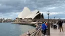 Warga berjalan di sepanjang Sydney Harbour dengan latar belakang pemandangan Sydney Opera House di Sydney pada 30 Desember 2017 (atas) dan pada 8 Maret 2020. (Saeed KHAN/AFP)