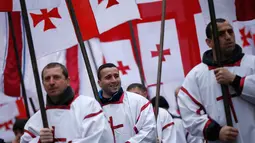 Peserta "Alilo" memegang bendera selama mengikuti pawai bersama di jalanan Tbilisi, Georgia, Kamis (7/1). Para peserta ini merupakan penganut Kristen Ortodoks di Georgia. (REUTERS/David Mdzinarishvili)