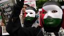 Para pengunjuk rasa yang mengenakan topeng dengan warna bendera Palestina memegang poster dalam aksi unjuk rasa untuk mendukung Palestina di luar Kedutaan Besar Amerika Serikat di Jakarta, Sabtu 13 Januari 2024. (AP Photo/Dita Alangkara)