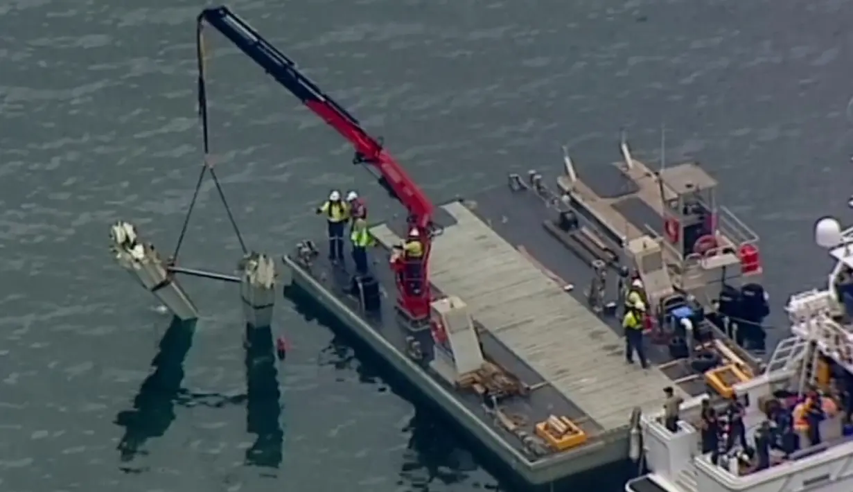 Petugas menggunakan derek dalam operasi pengangkatan bagian pesawat amfibi dari Sungai Hawkesbury, Sydney, Kamis (4/1). Bangkai pesawat jenis DHC-2 Beaver itu akan dikirim ke fasilitas yang aman guna diperiksa penyelidik. (Mick Tsikas/AAP Images via AP)