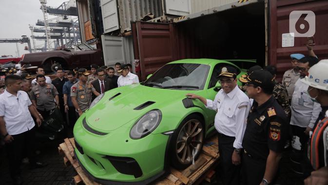 Menhub Budi Karya Sumadi (kedua kanan) mengecek barang bukti kasus penyelundupan mobil dan motor mewah di Terminal Petikemas Koja, Jakarta, Selasa (17/12/2019). Bea Cukai menggagalkan penyelundupan 19 unit mobil mewah, 35 unit motor mewah, rangka, dan mesin. (merdeka.com/Iqbal Nugroho)
