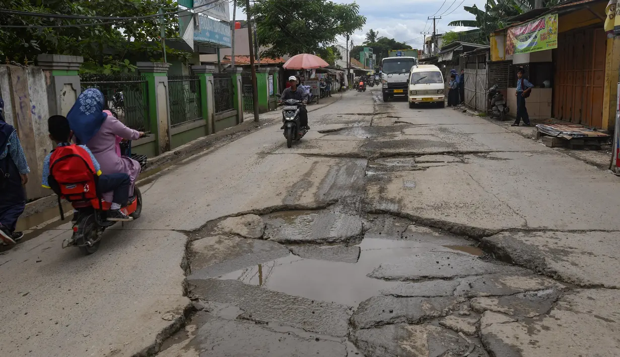 Warga melewati jalan yang rusak parah di Jalan Raya Tanjung Pasir, Tangerang, Banten, Rabu (22/1/2025). (merdeka.com/Arie Basuki)