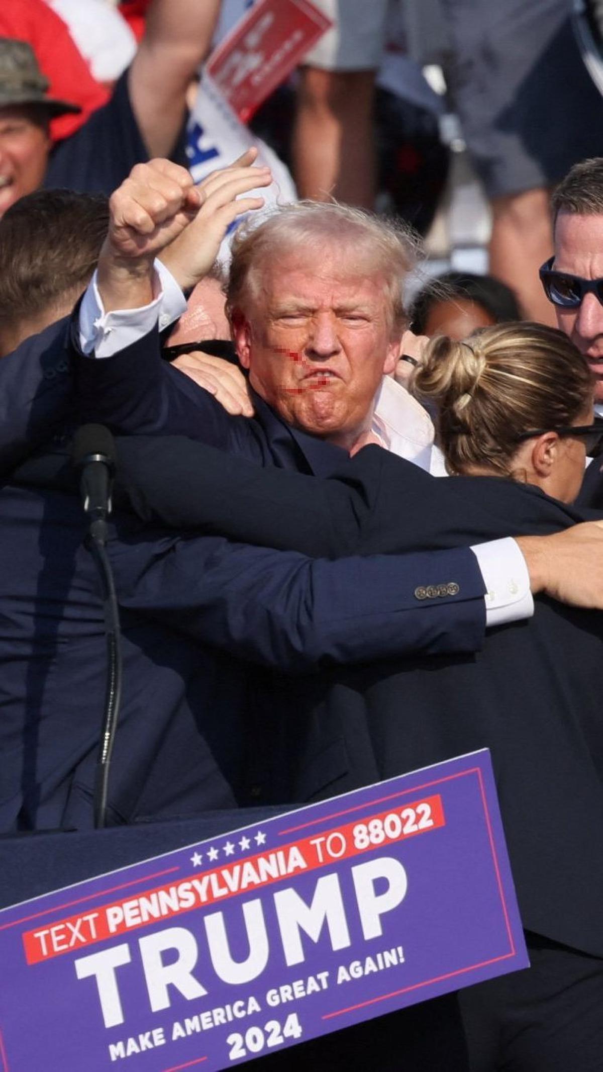 Dengan darah berceceran di wajah dan telinganya, Donald Trump mengangkat kepalan tangan. "Lawan!" katanya. "Lawan!"  Foto: Reuters