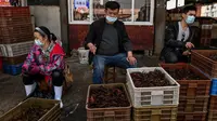 Pedagang mengenakan masker saat menawarkan udang untuk dijual di Pasar Baishazhou Wuhan di Wuhan, provinsi Hubei, Rabu (15/4/2020). Lebih dari 90 persen kios pasar basah di Wuhan telah kembali buka sejak pemerintah mencabut aturan lockdown di wilayah pusat wabah tersebut. (Hector RETAMAL/AFP)