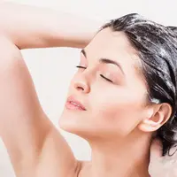 Ilustrasi wanita sedang berkeramas untuk membersihkan rambut.