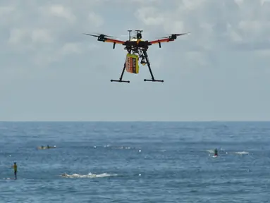 Pesawat tak berawak (drone) pendeteksi hiu berpatroli di atas para peselancar di Pantai Bilgola, utara Sydney, Australia, 10 Desember 2017. Drone ini dilengkapi sistem yang mampu mendeteksi predator bawah air dengan cepat dari udara. (PETER PARKS/AFP)