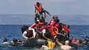 Seorang pengungsi mengangkat anaknya saat perahu mereka kempes di Pulau Lesbos, Yunani (13/9/2015). Menurut Organisasi Internasional untuk Migrasi (IMO) diperkirakan 309.000 orang telah tiba melalui laut di Yunani (REUTERS / Alkis Konstantinidis)