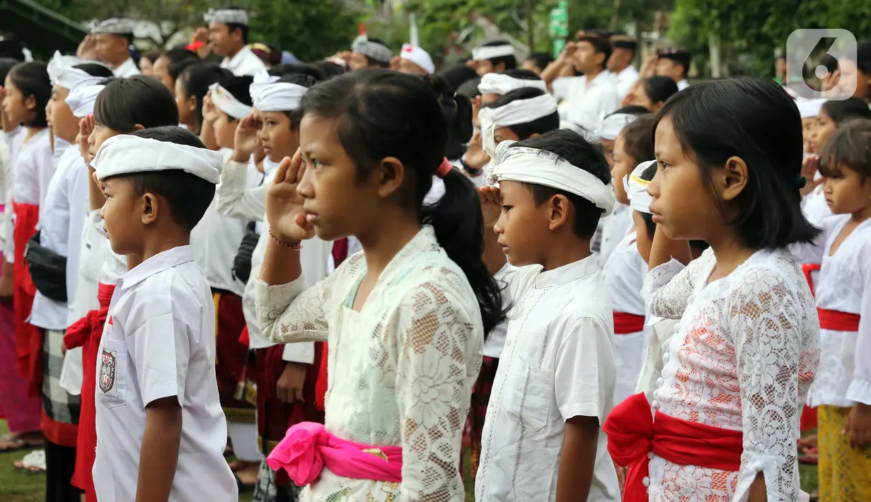 Pelajar Sekolah Dasar menggunakan pakaian adat saat mengikuti upacara peringatan detik-detik Proklamasi di halaman Tugu Pahlawan Banjar Penglipuran, Kabupaten Bangli, Bali, Kamis (17/8/2023). (Liputan6.com/Helmi Fithriansyah)