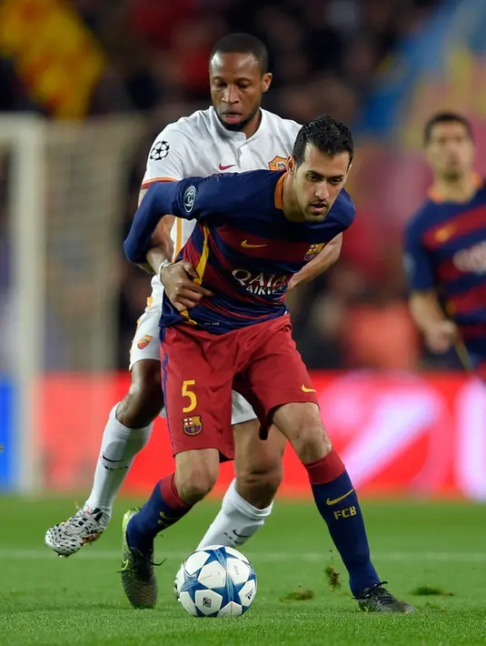 Gelandang AS Roma, Seydou Keita (kiri) berusaha merebut bola dari gelandang Barcelona, Sergio Busquets pada laga Grup E Liga Champions di Camp Nou, Spanyol, Rabu (25/11). Barcelona menang telak atas AS Roma dengan skor 6-1. (AFP/Lluis GENE)