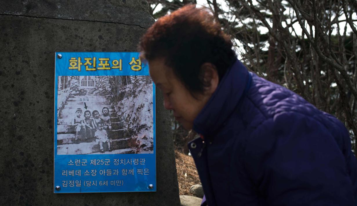 Pengunjung berjalan melewati sebuah poster yang menunjukkan gambar masa kecil Kim Jong Il saat berusia enam tahun di Kastil Hwajinpo, yang merupakan rumah pendiri Korea Utara Kim Il Sung, di Pantai Hwajinpo, Korea Selatan,(19/2). (AP Photo/Jae C. Hong)