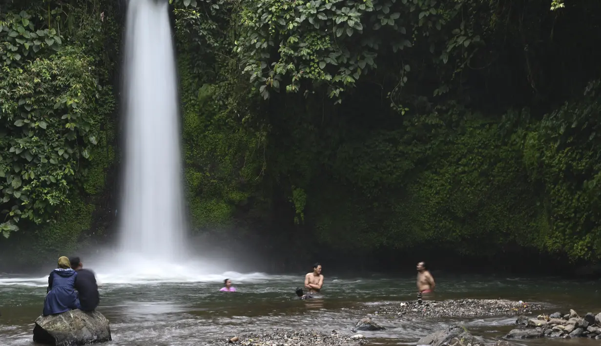 Orang-orang mengunjungi Air Terjun Sengkuang, salah satu tempat wisata di Kepahiang, Provinsi Bengkulu pada 1 Mei 2021. Air Terjun Sengkuang masih sangat indah, asri serta suasana lokasi tersebut masih sunyi dan cocok untuk pengunjung yang ingin mencari ketenangan. (ADEK BERRY / AFP)