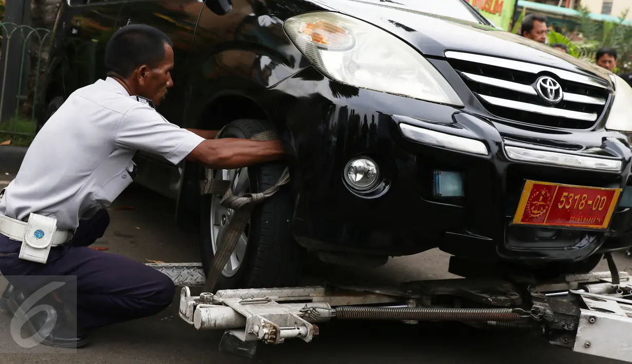 Petugas Dishub memasang tali derek saat razia parkir liar di kawasan Tanah Abang, Jakarta, Senin (14/11). Meski sudah ditertibkan, pengendara masih tak menghiraukan peraturan tersebut yang mengakibatkan kemacetan. (Liputan6.com/Gempur M Surya)