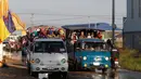 Para pekerja menaiki mobil bak terbuka sebagai transportasi harian mereka pulang ke rumah dari tempat kerja di sebuah pabrik di dekat desa Trapang Anchanh, di luar Phnom Penh, Kamboja (27/10). (AP Photo/Heng Sinith)
