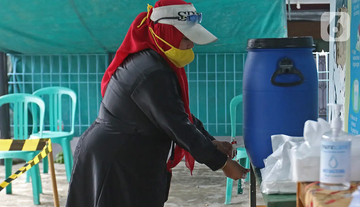 Warga mencuci tangan sebelum menggunakan hak pilihnya dalam Pilkada Depok di TPS 56, Mekarjaya, Depok, Rabu (9/12/2020). TPS 56 menggunakan tema kesehatan untuk menarik warga menggunakan hak pilih dan mengingatkan protokol kesehatan di masa Pandemi COVID-19. (Liputan6.com/Herman Zakharia)
