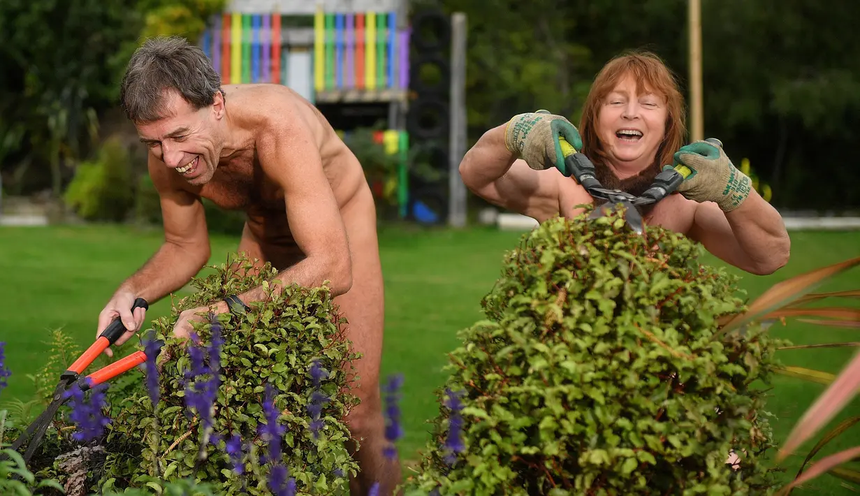 Brent Anderson (kiri) dan Robyn Beach memangkas tanaman saat berpartisipasi dalam World Naked Gardening Day di Wellington Naturist Club di Upper Hutt, Wellington , Selandia Baru (5/5). Acara ini sudah ada sejak 2015. (AFP Photo/Marty Melville)