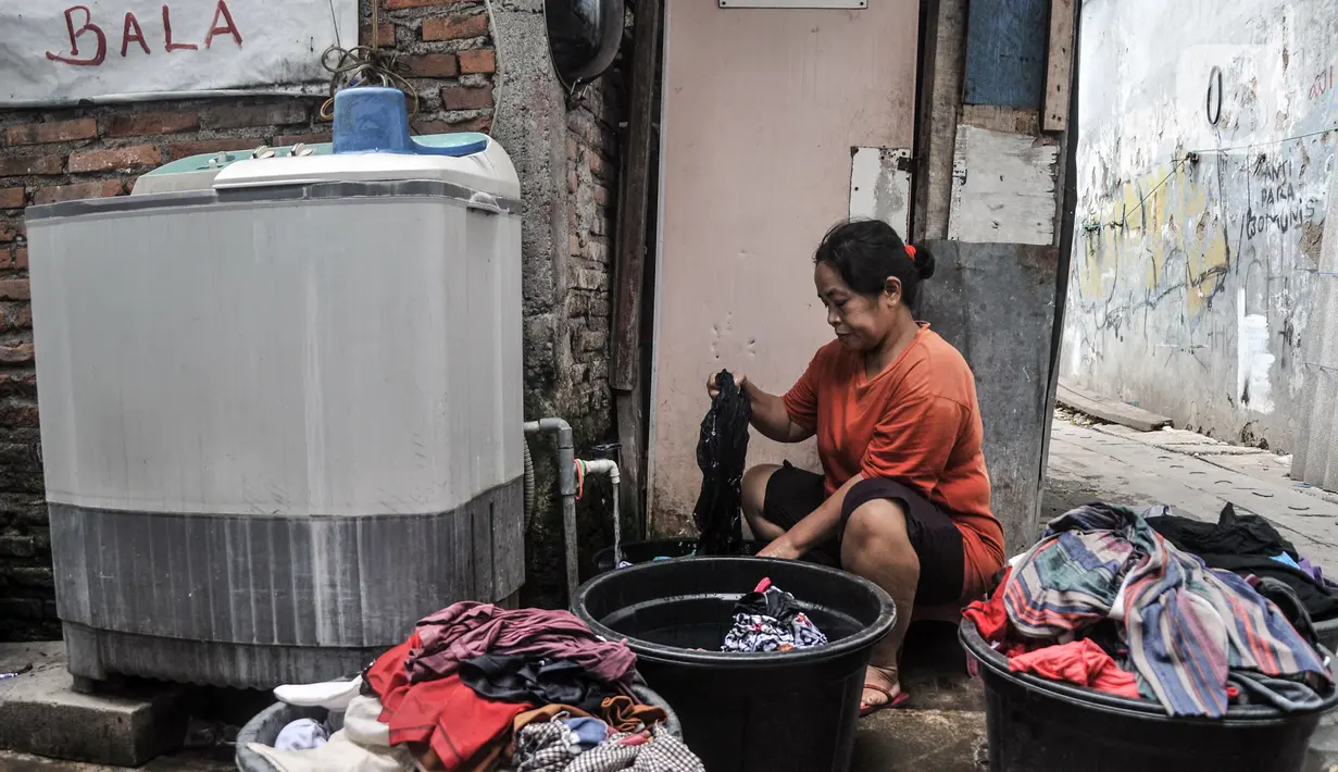 Warga mencuci pakaian menggunakan air tampungan di Kampung Baru Kubur, Penjaringan, Jakarta Utara, Selasa (11/1/2022). Krisis air bersih memaksa warga membeli air dari pedagang keliling dan kemudian ditampung dalam drum atau bak. (merdeka.com/Iqbal S. Nugroho)