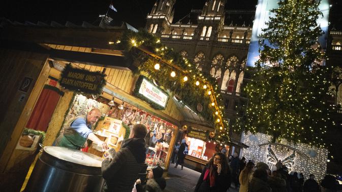 Seorang pria menjual chestnut asap dan kentang panggang di pasar Natal di depan balai kota Wina di Wina, Austria (19/11/2019). Setiap November hingga Natal tiba, Wina di Austria dikenal sebagai kota penyelenggara pasar malam Natal tertua di dunia. (AFP Photo/Joe Klamar)