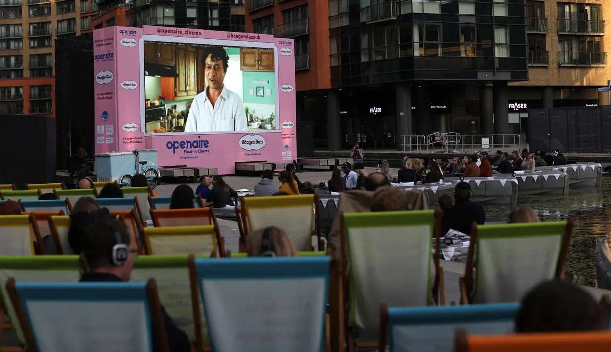 Orang-orang duduk menonton film pada layar lebar saat acara pratinjau bioskop apung di Merchant Square di Kanal Regent, London, Rabu (1/9/2020). Bioskop bernama Openaireini itu memberi dua pilihan tempat duduk kepada penonton, yakni duduk di perahu atau di kursi di tepi kanal. (ISABEL INFANTES/AFP)