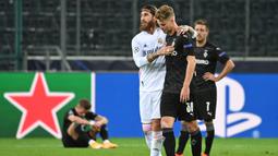 Bek Real Madrid, Sergio Ramos, bersama bek Borussia Monchengladbach, Nico Elvedi, usai pertandingan Liga Champions di Borussia Park, Rabu (28/10/2020) dini hari WIB. Real Madrid bermain imbang 2-2 lawan Borussia Monchengladbach. (AFP/Ina Fassbender)