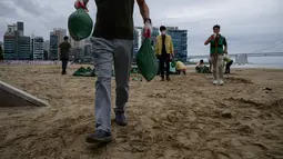 Anggota dewan distrik mengisi kantong pasir sebagai bagian dari persiapan menjelang kedatangan topan Maysak, di pantai Gwangalli di Busan (2/9/2020). Penerbangan di-grounded di Korea Selatan dan peringatan badai dikeluarkan di kedua sisi semenanjung Korea. (AFP/Ed Jones)