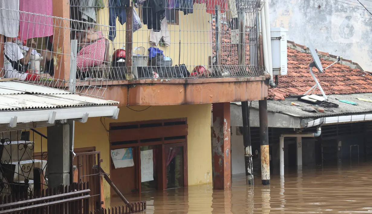 Warga beristirahat di lantai dua tempat tinggalnya di Kawasan Rawajati yang tergenang banjir, Jakarta, Rabu Rabu (1/1/2020). Hujan yang mengguyur Jakarta sejak Selasa sore (31/12/2019) mengakibatkan banjir di sejumlah titik di Jakarta. (Liputan6.com/Helmi Fithriansyah)