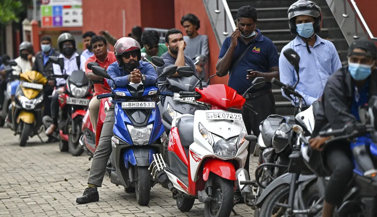Pengendara motor mengantre di sepanjang jalan untuk membeli bahan bakar dari stasiun bahan bakar Lanka IOC di Kolombo, Selasa (24/5/2022). Sri Lanka yang kekurangan uang menaikkan harga bahan bakar secara tajam ke rekor tertinggi pada 24 Mei 2022, menyebabkan penderitaan lebih lanjut bagi 22 juta orang di negara itu dalam krisis terburuk sejak kemerdekaan. (Ishara S. KODIKARA / AFP)
