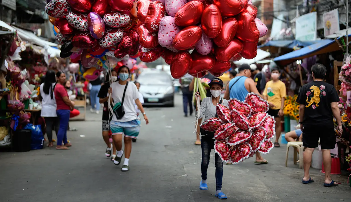 Penjual balon berbentuk hati menjajakan dagangannya di pasar bunga di Manila, Filipina, Senin (13/2/2023). Harga bunga naik karena tingginya permintaan sehari sebelum Hari Valentine. (AP Photo/Aaron Favila)