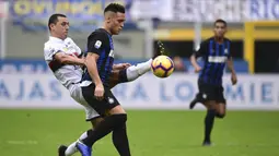 Striker Inter Milan, Lautaro Martinez, berebut bola dengan gelandang Genoa, Romulo, pada laga Serie A Italia di Stadion San Siro, Milan, Sabtu (3/11). Inter menang 5-0 atas Cagliari. (AFP/Miguel Medina)