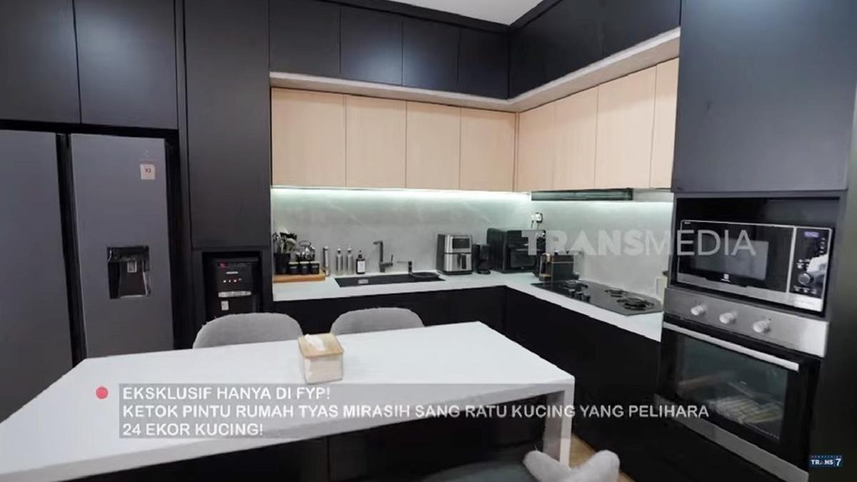Tepat di sebelah ruang tengah, terdapat dapur yang rapi dan estetik dengan dominasi warna hitam. Dapur ini dilengkapi oven dan kulkas dua pintu.<br>