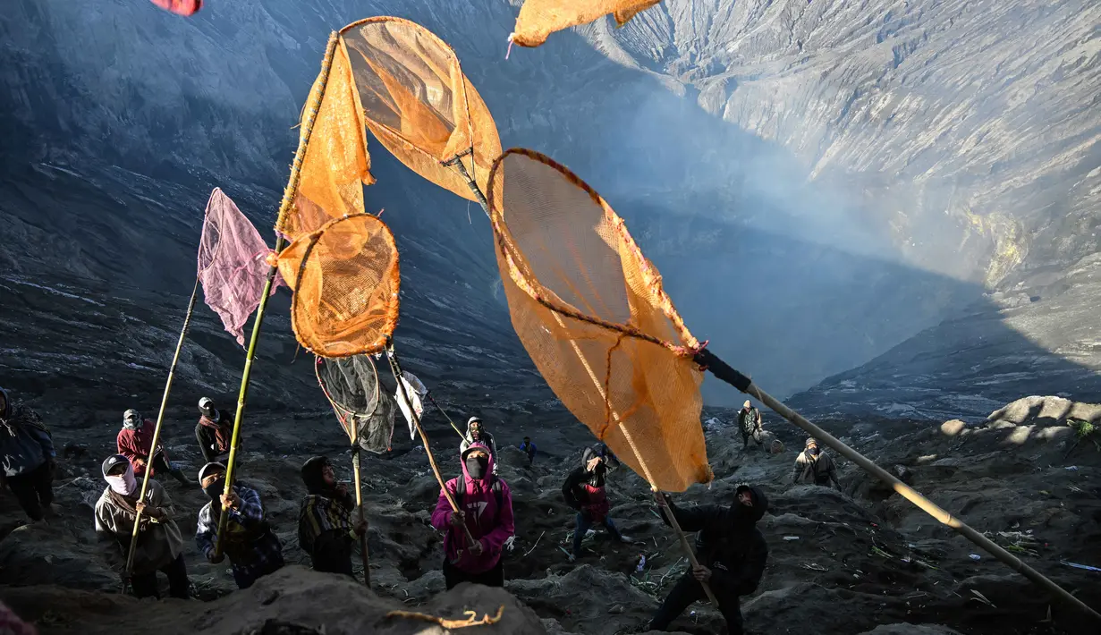 Warga desa menangkap persembahan yang dilemparkan oleh umat Hindu dari komunitas Tengger ke kawah Gunung Bromo selama festival Yadnya Kasada di dekat Probolinggo, Jawa Timur, Senin 1 Juni 2026. (JUNI KRISWANTO/AFP)